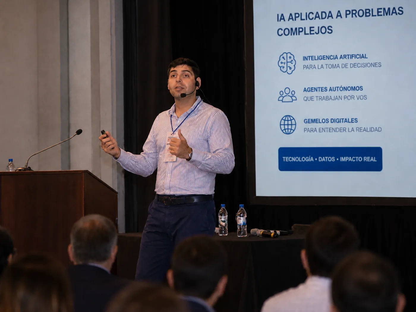 Omar Rivas presentando en un escenario una charla sobre inteligencia artificial aplicada a problemas complejos.
